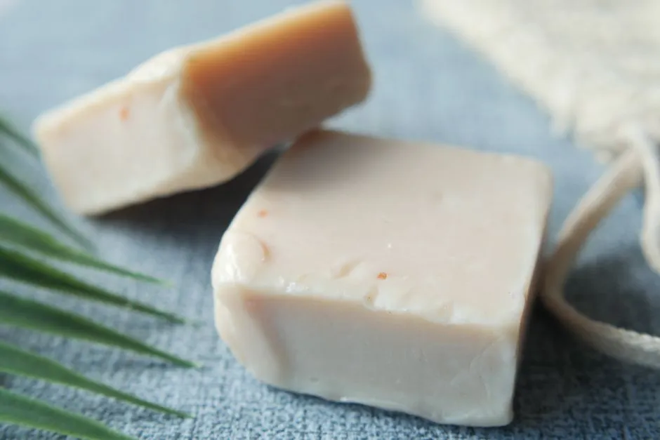 Two blocks of natural handmade soap on a textured surface, perfect for personal care stocks.